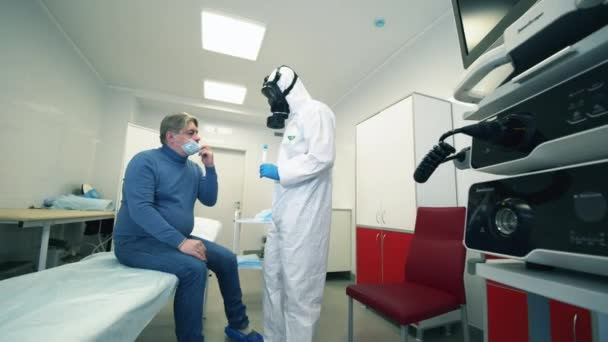 Specialist på en hazmatdräkt tar patienter saliv för diagnostik — Stockvideo
