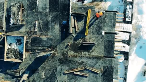 Вид сверху на многоэтажную стройплощадку с рабочими — стоковое видео