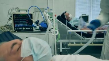 Coronavirus, kovid 19 hastası bir hastanede yoğun bakımda. Bir doktor koronavirüs hastasını tedavi ederken solunum cihazını takıyor..