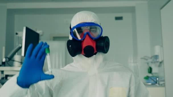 Persoon in hazmat houdt een buis met een monster voor coronavirus. — Stockvideo