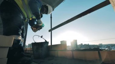 İnşaat işçisi bir inşaat alanında. Tuğla döşeme işi erkek bir müteahhit tarafından yürütülüyor.