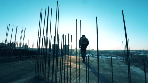 El trabajador está caminando a lo largo del sitio de construcción abierto con un martillo. Trabajador de la construcción en un sitio de construcción . — Vídeos de Stock