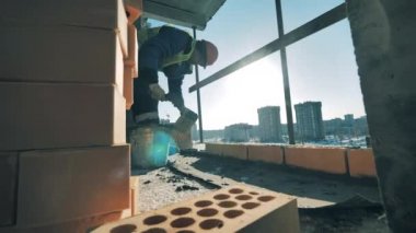 İnşaat işçisi taze betona tuğla örüyor. İnşaat işçisi inşaat alanında..