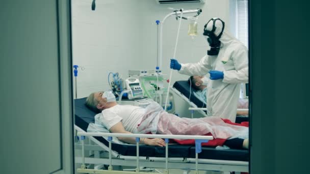 Doctor in hazmat treats a person with coronavirus in hospital. Coronavirus, covid-19 patient in intensive care unit at a hospital. — Stock Video