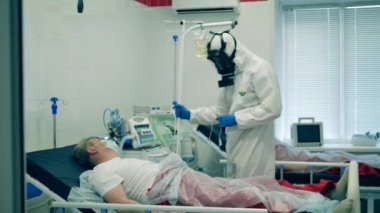 Koruyucu giysili bir doktor salgın sırasında hastaya serum veriyor. Coronavirus, kovid 19 hastası bir hastanede yoğun bakımda..