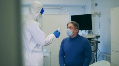 Doktor, koronavirüs salgını sırasında hastaların sıcaklığını ölçer..