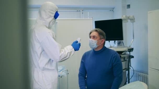Врач измеряет температуру пациентов во время пандемии коронавируса . — стоковое видео