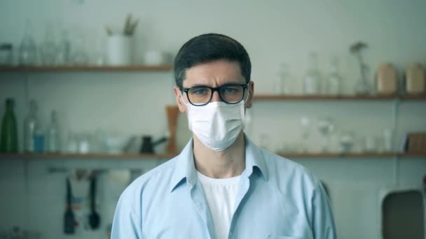 Ein Porträt eines Mannes mit Brille nimmt eine medizinische Maske ab und lächelt — Stockvideo