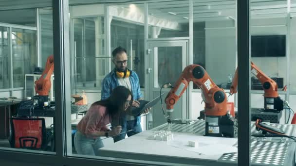 De jeunes chercheurs examinent des machines robotiques en mouvement — Video