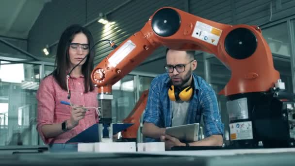 Estudiantes de secundaria que estudian robótica en el laboratorio universitario. Dos ingenieros están mirando un dispositivo similar a un robot en movimiento — Vídeos de Stock