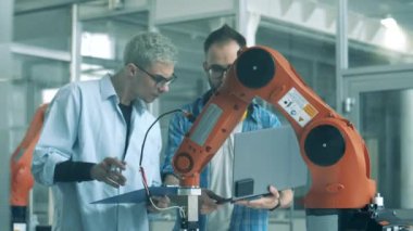 İki araştırmacı bir robotik deneyi tartışıyor.