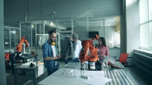 Genç mühendisler laboratuvar robotlarıyla yapılan bir deneyi denetliyorlar. — Stok video