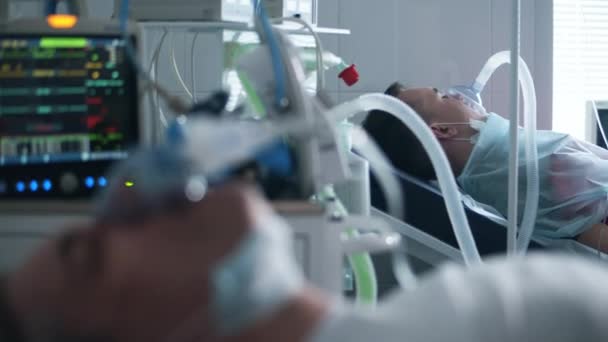 Muž s ventilátorem ležící na klinickém oddělení během pandemie koronaviru. — Stock video