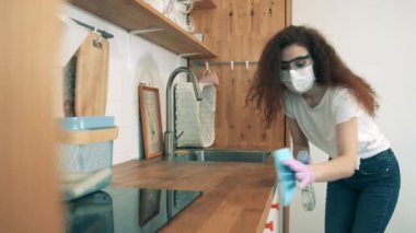 Coronavirus, COVID-19 önleme konsepti. Bir bayan dezenfektanla masa yüzeyini temizliyor.