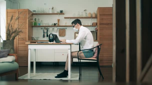 Workimg from home during coronavirus pandemic. A man with no pants on is working on a computer from home — Stock Video