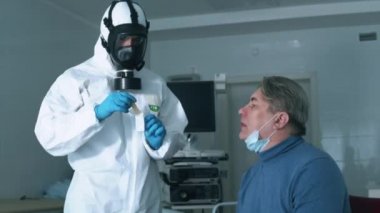 Bir doktor koronavirüs salgını sırasında hastaların boğazlarını kontrol ediyor. Coronavirus, hastahanedeki test sırasında kovid 19 enfekte olmuş hasta..
