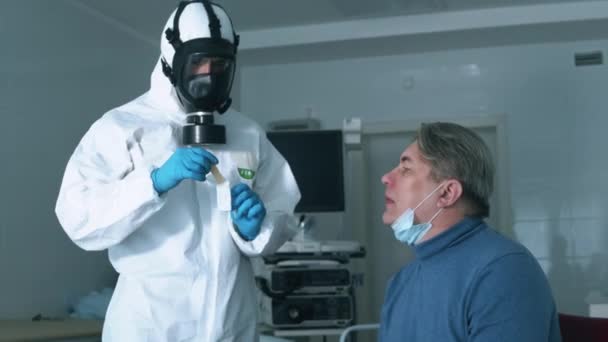 Jeden lékař zkontroluje hrdlo pacientů během pandemie koronaviru. Koronavirus, covid-19 Infekovaný pacient během vyšetření v nemocnici. — Stock video