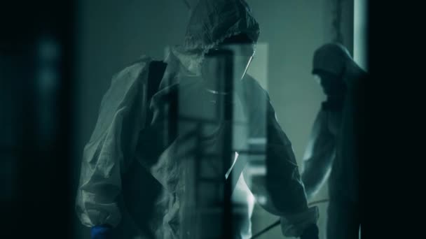 Inspetores sanitários filmados através de vidro durante a desinfecção. pandemia de coronavírus, prevenção de vírus, conceito COVID-19 . — Vídeo de Stock