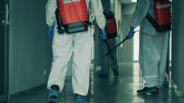 Coronavirus-Pandemie, Virusprävention, COVID-19-Konzept. Gruppe von Sanitärexperten sprüht Chemikalien in der Halle — Stockvideo