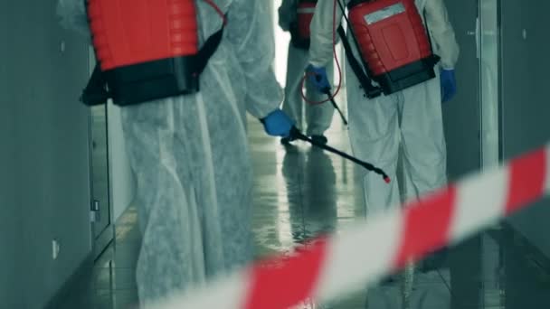 Холла дезинфицирует группа рабочих в брызгающих костюмах — стоковое видео