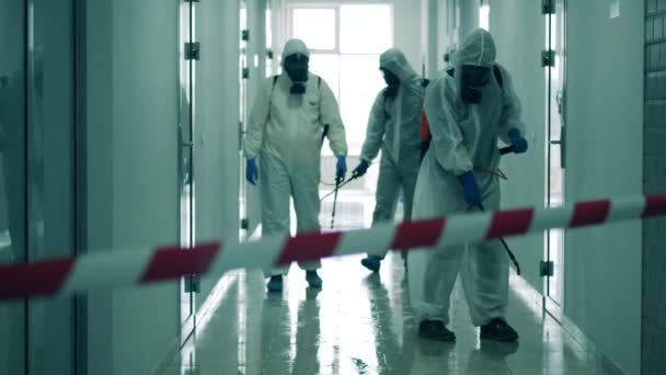 Especialistas en trajes de salpicadura están desinfectando un pasillo — Vídeos de Stock