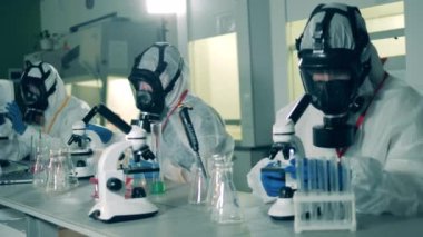 Tehlikeli madde uzmanları laboratuarda koronavirüs testleriyle çalışırlar..