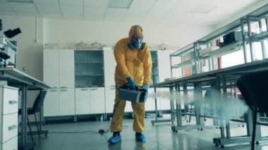 Bir adam salgın sırasında odayı sterilize etmek için sprey kullanıyor..