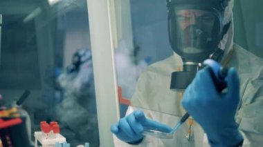 Erkek işçi, laboratuarda aşı geliştirirken pipette kullanıyor..
