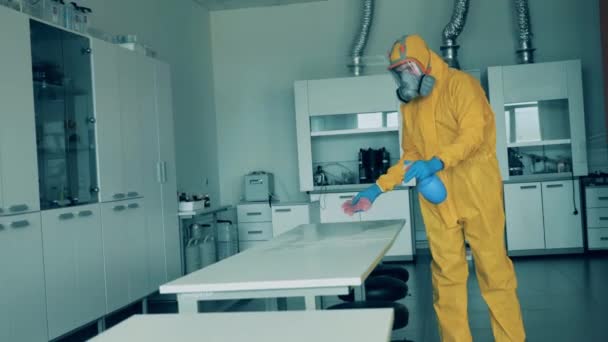 Ein Arbeiter im Schutzanzug reinigt einen Tisch mit Antiseptikum. — Stockvideo