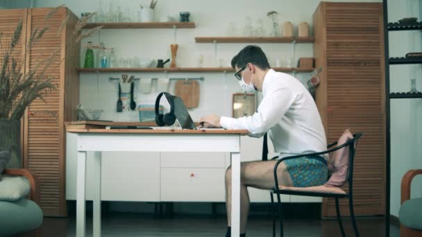 Un hombre trabaja desde casa, usando un portátil durante la cuarentena. Educación a distancia, concepto de aprendizaje a distancia . — Vídeo de stock