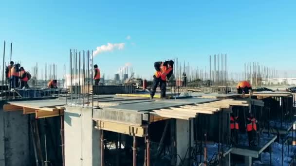 Trabalhadores estão fazendo obras de construção em cima de um edifício de vários andares — Vídeo de Stock