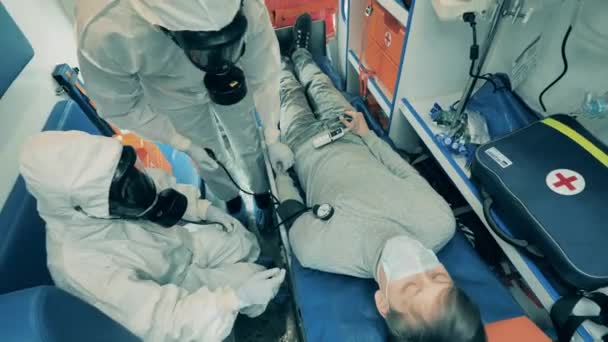 I medici controllano il paziente durante il ricovero in ambulanza. Epidemia di coronavirus, pandemia di covid-19, concetto di malattia virale . — Video Stock