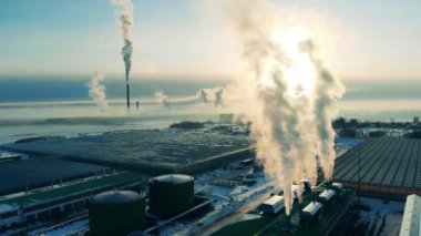 Dalgalanan bacaları olan bir fabrika kompleksinin manzarası. Yukarıdan gelen enerji fabrikası, bacadan çıkan buhar..