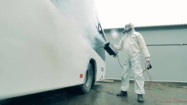 Dezenfekte, dezenfekte konsepti. Temizlik işçisi salgın sırasında virüsü öldürmek için otobüse sprey sıkıyor..