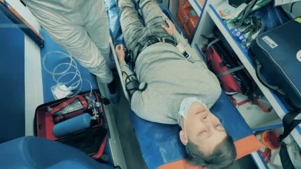 Врач помогает человеку во время госпитализации в машине скорой помощи. Эпидемия коронавируса, пандемия ковида-19, концепция вирусных заболеваний . — стоковое видео