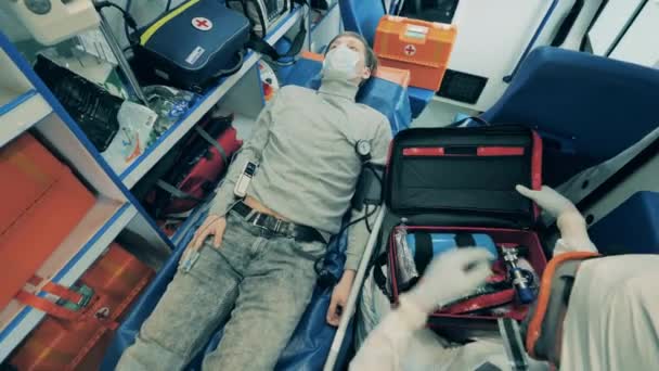 Врач в защитном костюме и пациент в машине скорой помощи — стоковое видео