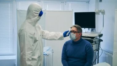 Doktor, hastaların sıcaklıklarını kızılötesi termometreyle kontrol ediyor.