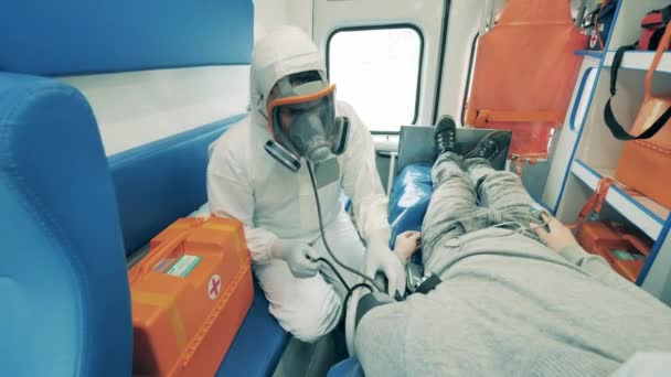 Paramedicus in een hazmat pak meet patiëntendruk — Stockvideo