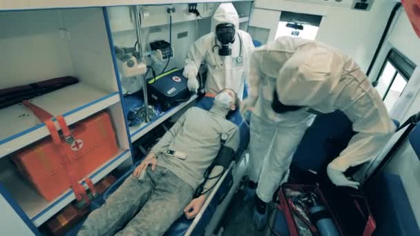 Dwóch pracowników medycznych daje hospitalizowanemu pacjentowi balon do oddychania.. — Wideo stockowe