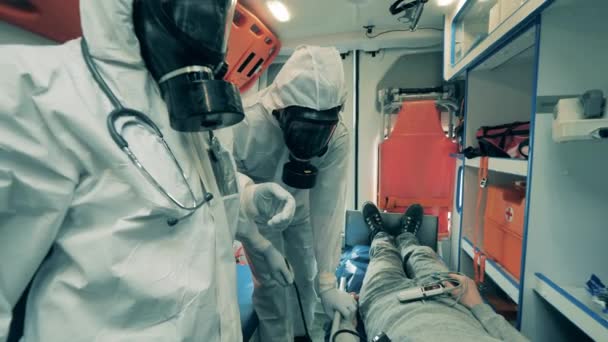Врачи скорой помощи в защитных костюмах проверяют пациента — стоковое видео