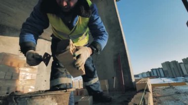 Erkek işçi beton saçıyor ve tuğla örüyor.
