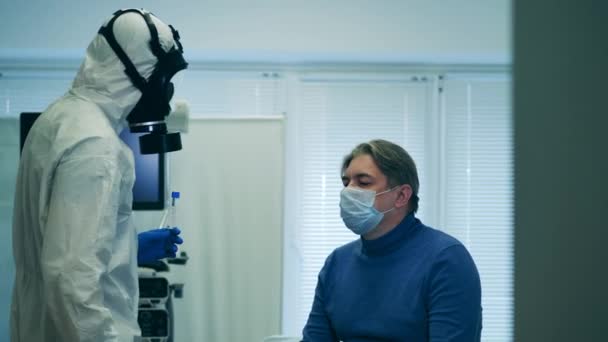 Un paramédico en traje de salpicadura está tomando saliva a los pacientes para una prueba. Cribado del paciente covid-19, síntomas del coronavirus . — Vídeo de stock