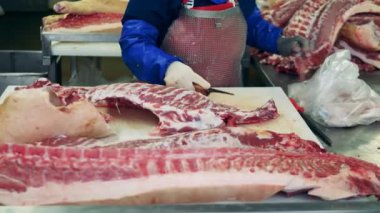 Bitki işçisi büyük parça kemik eti oyuyor. Gıda üretimi, et, domuz üretim fabrikası.