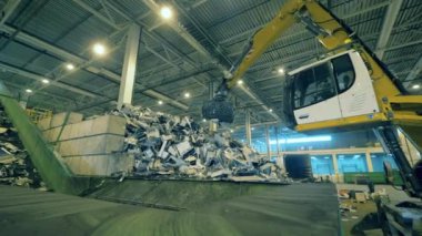 Kazı makinesi atılmış elektronik enkazı bir konteynıra koyuyor.