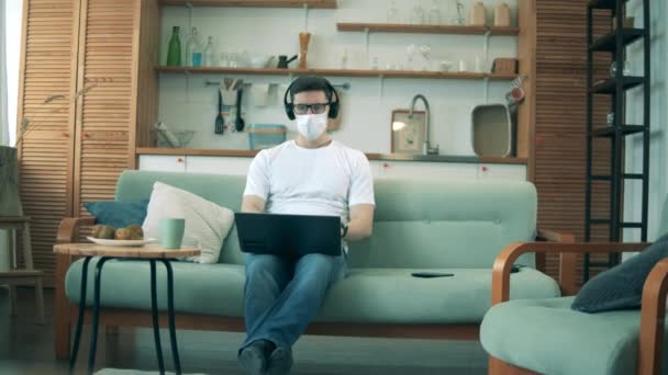 Man in medical mask works from home during quarantine. — Stock Video