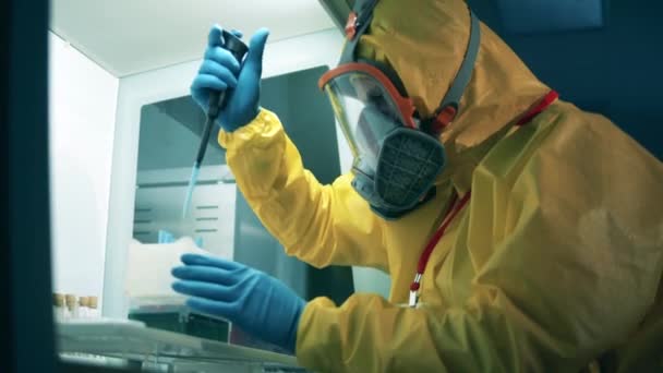 Antilichamen onderzoek cocnept, covid-19 coronavirus pandemie. Een persoon in een hazmat pak doet chemisch onderzoek. — Stockvideo