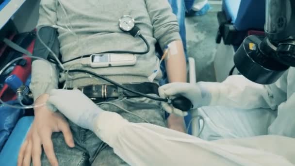 A physician measures male patients pressure in ambulance car. — Stock Video