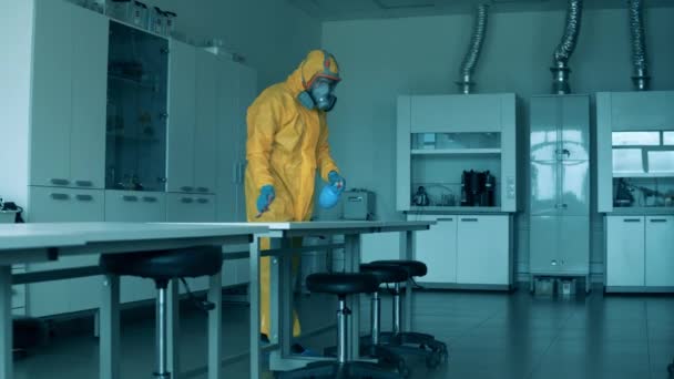 Санітарний працівник дезінфікує таблиці в лабораторії — стокове відео