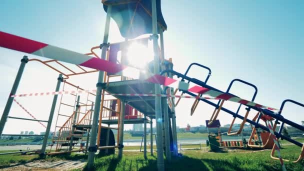 Nastro di avvertimento che limita l'ingresso al parco giochi. Parco giochi vuoto durante la pandemia di coronavirus . — Video Stock