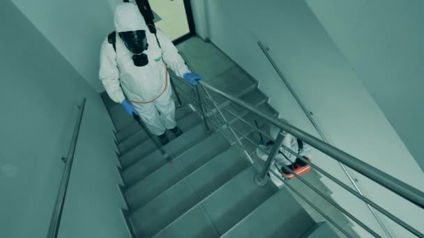 Dezinfektory čistí schodiště v kancelářské budově s antiseptiky. — Stock video